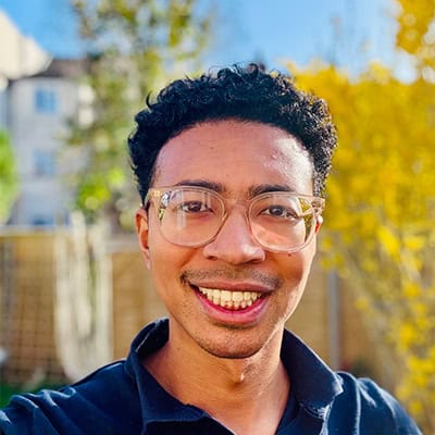 Man with black hear wearing glasses smiling