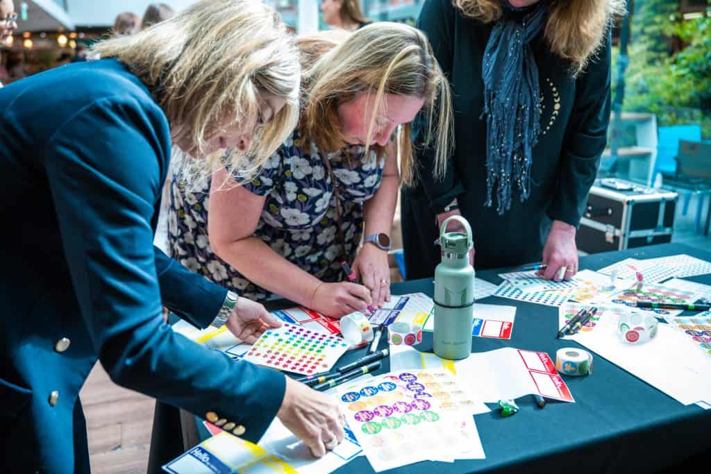 two women at a table with lots of stickers