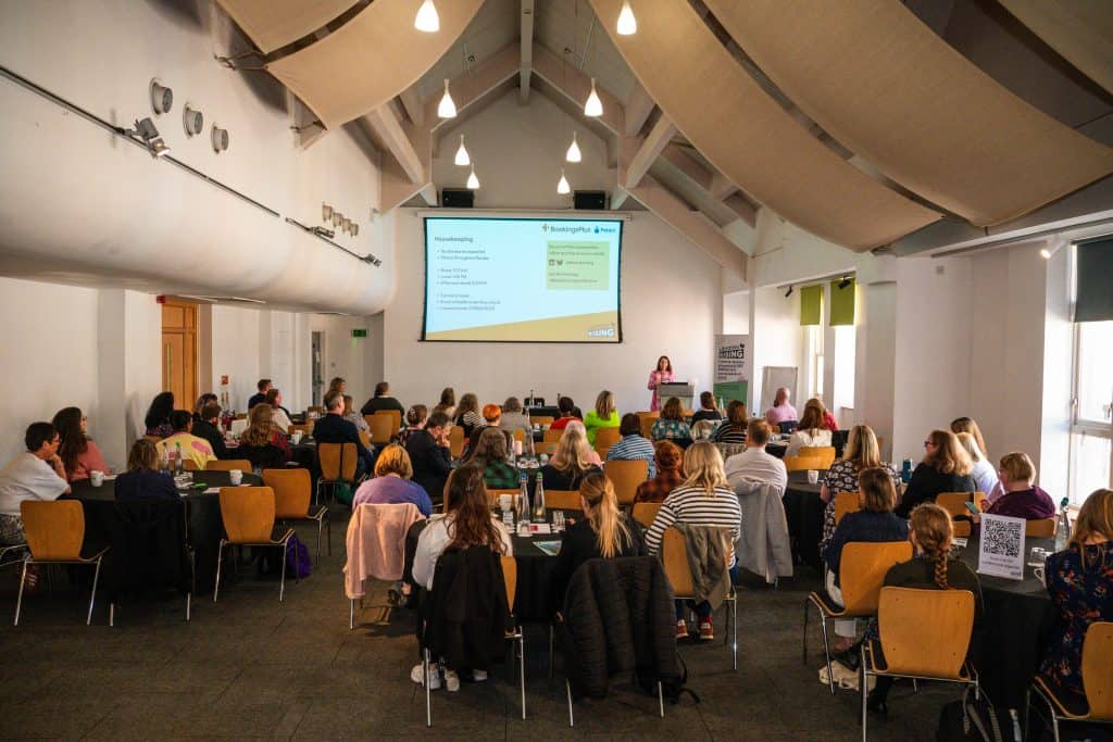 large conference room with tables full of people and projector screen